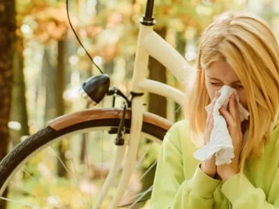 Woman bicycle autumn forest suffers from allergy.