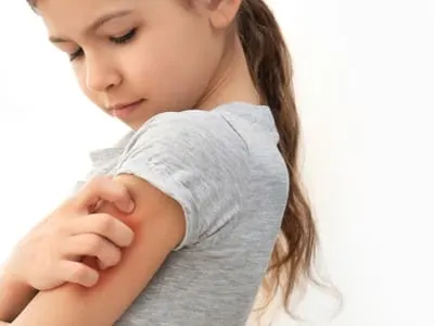 Little girl scratching arm indoors.