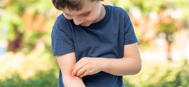 Child scratching and looking his arm