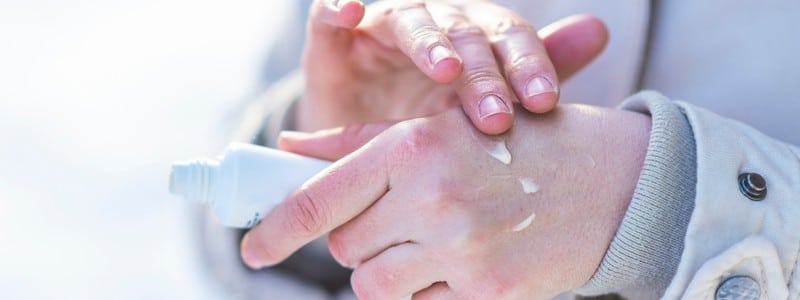 woman hand hydrating skin applying cream in winter.