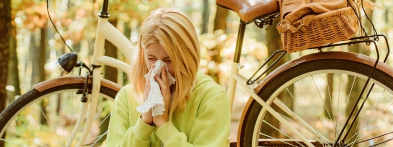 Woman bicycle autumn forest suffers from allergy.