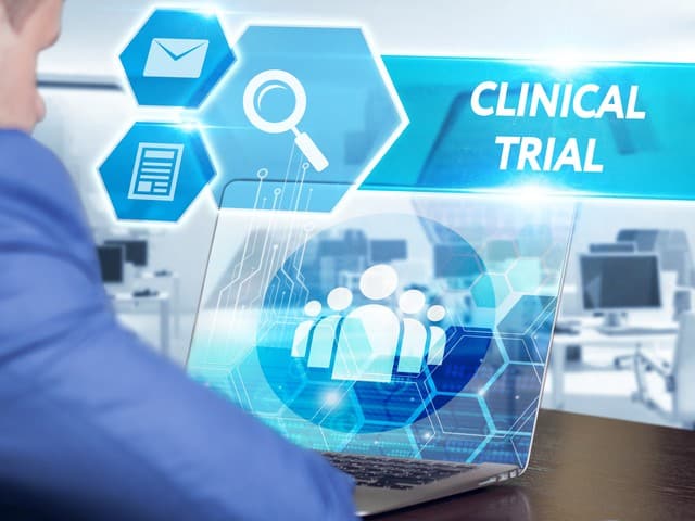 businessman working on his laptop in the office select the icon clinical trial
